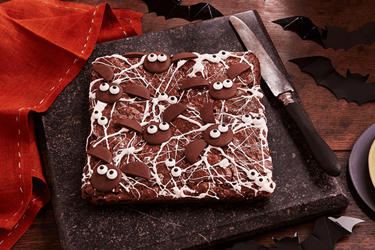 spooky Halloween cobweb brownies served on stone with knife kept aside