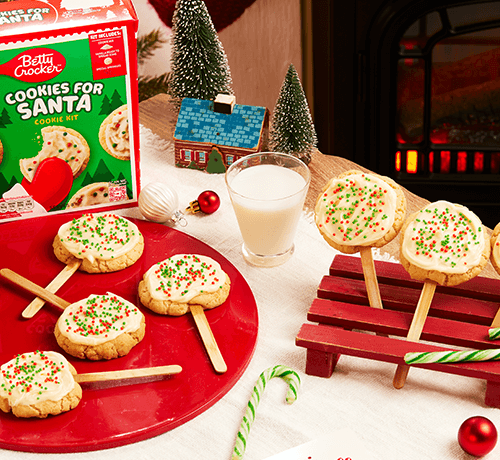 delicious cookie pops for Santa garnished with cream & colorful sprinkles served on a red plate on a Christmas decorated table